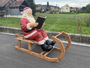 Weihnachtsmann auf Schlitten sitzend, liest im Buch