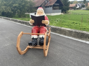 Grosser weihnachtsmann sitzt auf Rentierschlitten und liest in seinem Buch